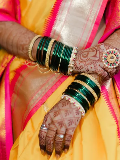 A close-up on the details: the intricate mehndi design and the traditional green glass bangles.