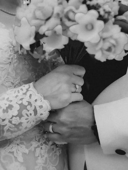 A close-up black and white shot of the couple's hands, showing their wedding rings. This detail shot is symbolic and beautifully composed.