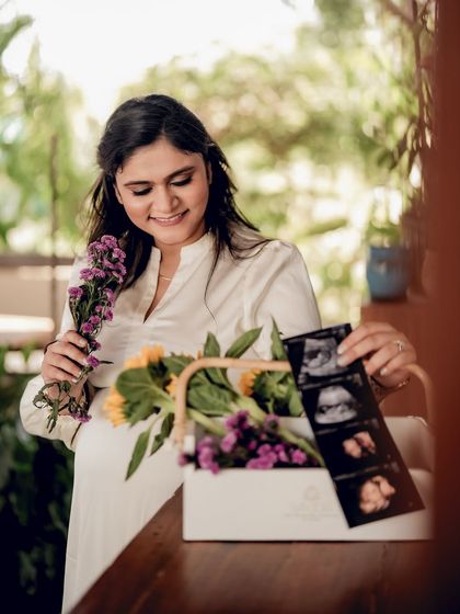 An indoor portrait of the mom-to-be looking at her sonogram pictures, surrounded by fresh flowers. It’s a sweet and colorful shot.