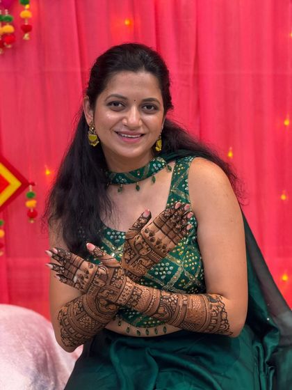 This lovely client is all smiles, showing off her beautiful mehendi against a festive backdrop. The design is perfect for any celebration.