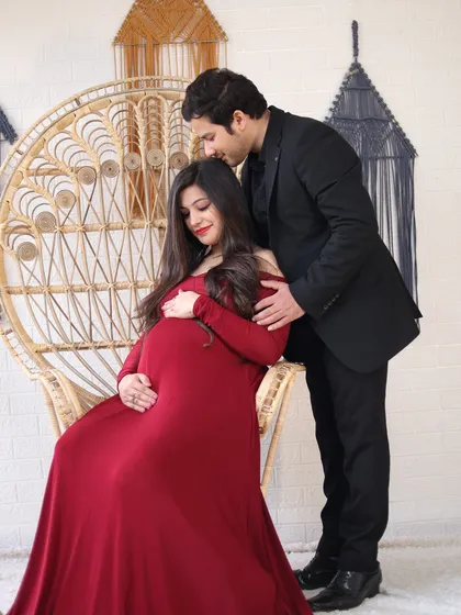 A loving couple's portrait in our studio, using a stylish peacock chair as a prop. This shot shows how we use props to add a unique and elegant touch to your maternity photos.
