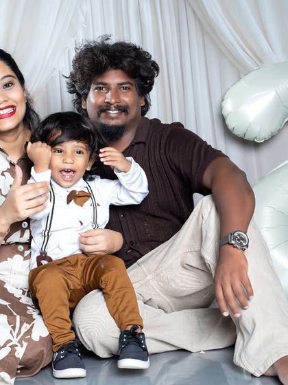 A happy family portrait for a second birthday, with the little boy giving a thumbs-up to the camera.