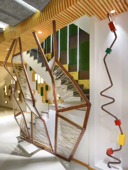 The staircase at the AMG office is a key architectural feature. The side wall is brought to life with a rhythmic composition of backlit maple wood hexagons, which also discreetly conceals electrical fixtures, perfectly marrying function with aesthetic form.