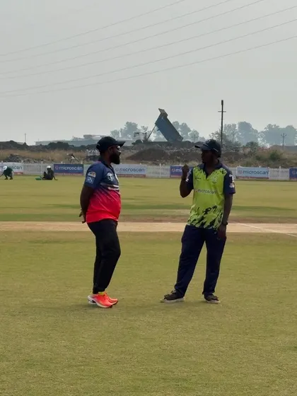 A candid moment between coaches on the field during a break in play. Sharing knowledge and experience is part of the game.