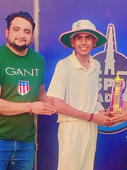 A young player in his cricket whites proudly accepts a trophy, a symbol of his dedication and achievement.