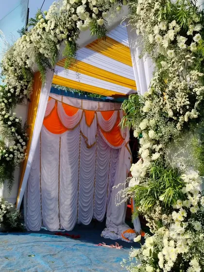 A simple yet elegant entrance for an outdoor event. This archway is covered in fresh white flowers and greenery, perfectly complementing the yellow and white drapes of the tent.