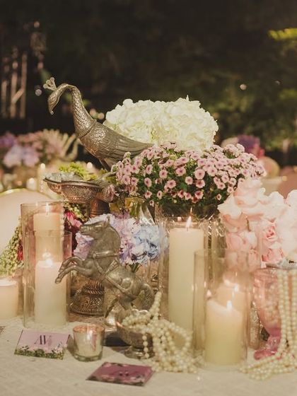 A beautiful table centerpiece featuring a silver peacock, candles, and soft florals, creating an atmosphere of refined elegance for the wedding dinner.