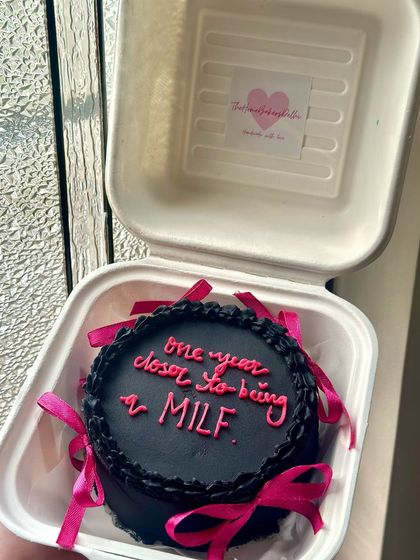 Our cheeky 'one year closer' bento cake, all packed up and ready to surprise someone. The contrast of the black frosting and pink ribbons is so striking.
