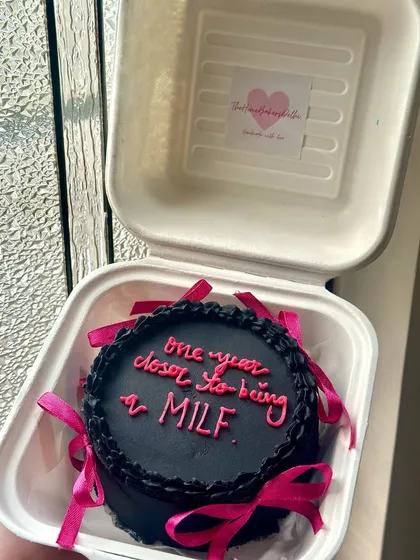 Our cheeky 'one year closer' bento cake, all packed up and ready to surprise someone. The contrast of the black frosting and pink ribbons is so striking.