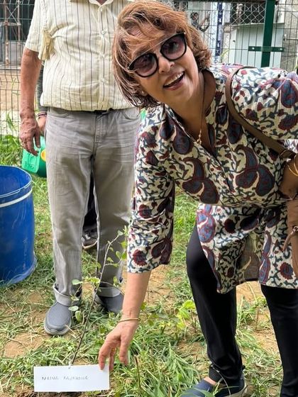 A smiling member of the DLF Senior Citizen Council places a name tag on a newly planted sapling, a personal touch to their contribution.