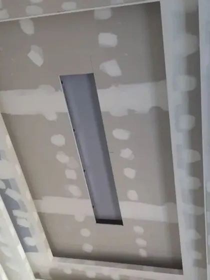 A close-up of a gypsum ceiling with a central recessed channel, likely for a large tube light or profile LED strip.