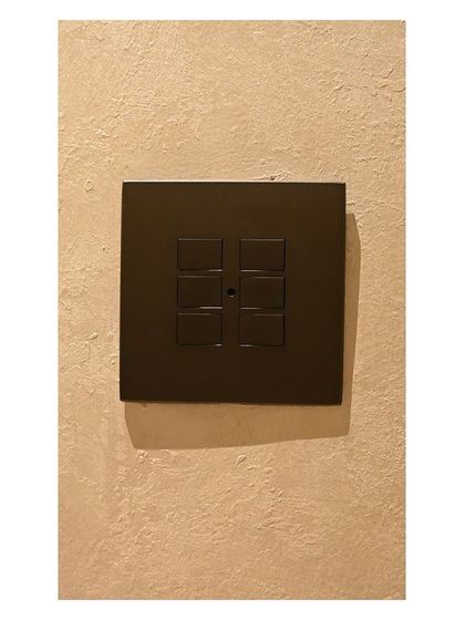 A close-up of a dark bronze smart keypad installed in a client's home. Notice how the finish complements the textured wall, demonstrating my focus on integrating tech with design.