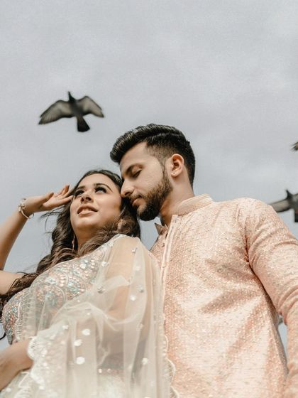 A low-angle shot that captures the couple against the sky with birds flying overhead. This creative perspective adds a sense of freedom and romance to their Jaipur pre-wedding portrait.
