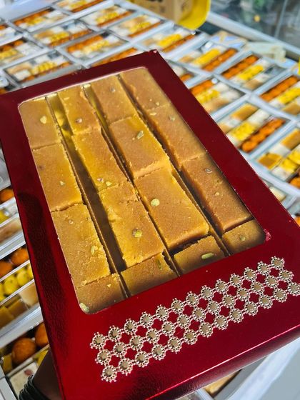 We offer a variety of packaging, including this vibrant red box filled with fresh Mysore Pak. It's a great way to make your festive gifts stand out while showcasing a taste of authentic South Indian sweets.