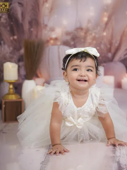 A simple and elegant portrait of a little girl in a beautiful white dress, crawling towards the camera with a happy smile.