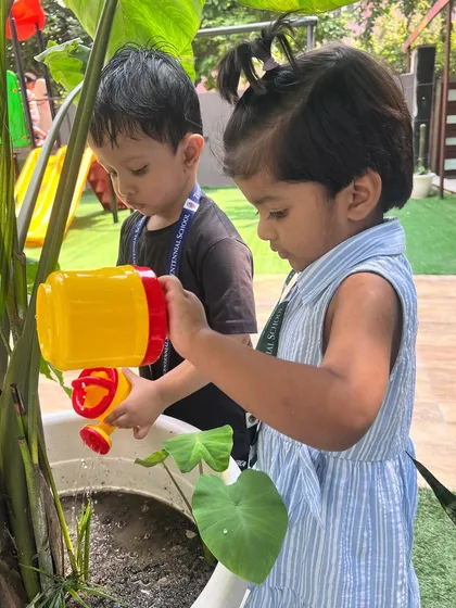 Our Red Butterfly class takes charge of watering the plants. This activity helps develop fine motor skills as they learn to handle the small watering cans with care.