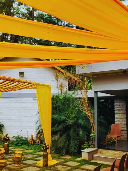 A classic Haldi ceremony setup featuring a bright yellow draped mandap, hanging marigolds, and traditional brass urlis for the ritual.
