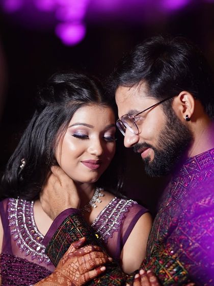 A romantic couple portrait from their sangeet. The bride's glamorous purple-toned makeup perfectly complements her outfit and the event's ambiance.