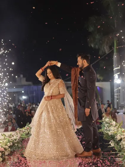 A fairytale dance moment on the reception stage, with the bride's lehenga and makeup catching the light perfectly.
