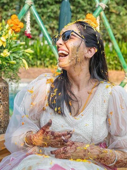 A candid shot of the bride laughing with joy, covered in turmeric during her Haldi ceremony. These are the happy moments we love to help create.