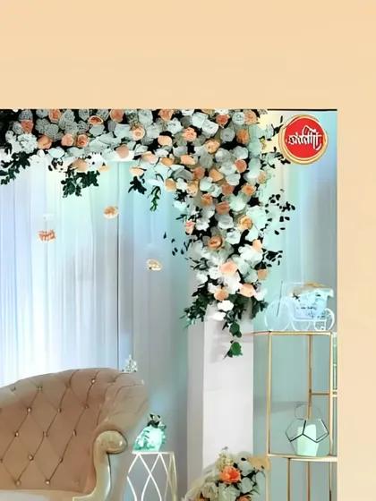 This shot captures the cascading corner floral piece, with peach and white roses flowing down against a soft, sheer curtain backdrop.