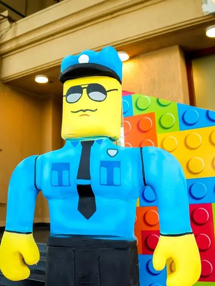 A LEGO policeman figure stands guard against a colorful brick wall.