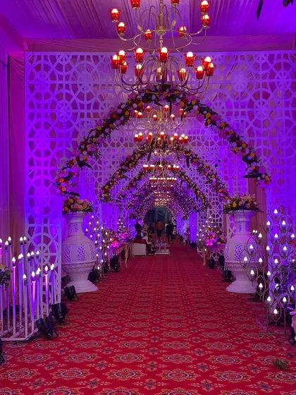 The full splendor of the purple-lit entrance, with chandeliers, floral arches, and candle stands creating a truly royal welcome.