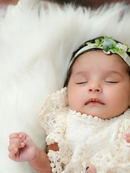 A sleeping angel in a nest of soft white fur. This newborn girl in her lace romper looks so peaceful and content.