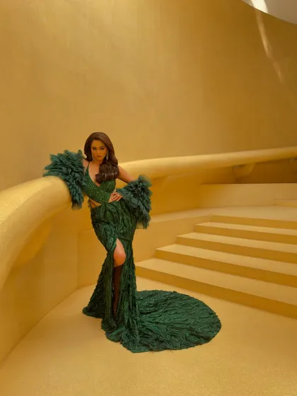 The full view of this stunning green gown shows off its dramatic train and silhouette. A perfect choice for a client looking to make a bold statement at a gala or reception.