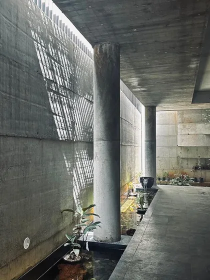 An exploration of light and shadow within a concrete passage. We believe architecture is an experience, and here we use natural light filtering through a skylit corridor to create dramatic, shifting patterns along a tranquil water feature.
