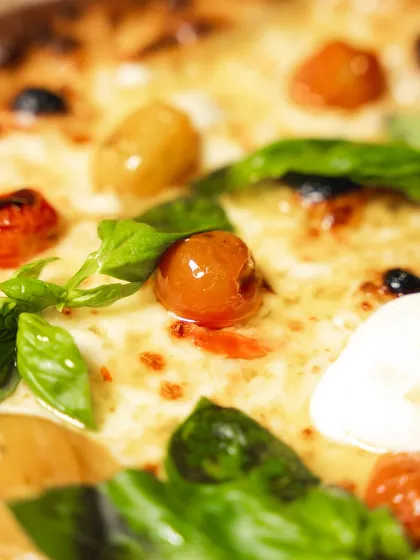 A macro shot of the toppings on our delivery-optimized pizza. The confit cherry tomatoes and fresh basil still look and taste vibrant after the journey.