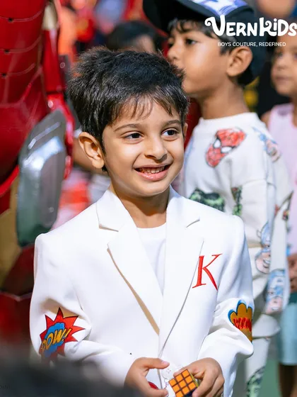 A smile that lights up the party. This close-up shows the joy of a boy wearing an outfit made just for him, featuring his initial and favorite comic book art.