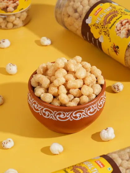 A bowl of flavored makhana snacks against a bright yellow background. We use color theory to create vibrant, eye-catching images for snack brands.
