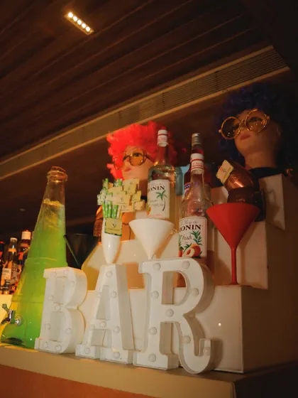 A fun and quirky bar setup for a themed party. The mannequin heads with colorful wigs and glasses add a playful and memorable touch to the decor.