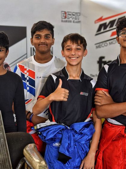 A group of young drivers in the pit lane, showcasing the camaraderie and focus within the paddock.
