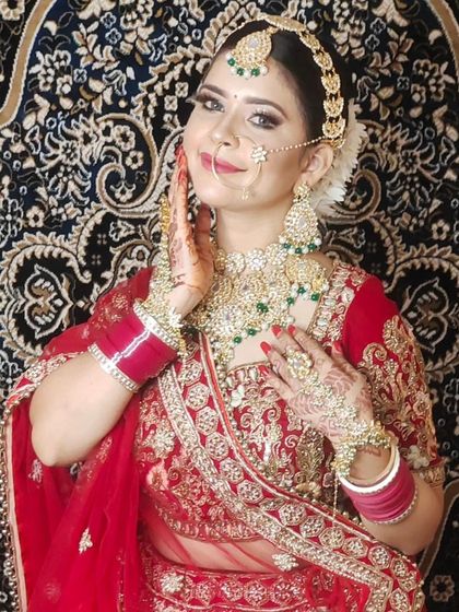 A happy bride in a classic red lehenga with heavy gold embroidery. This is a timeless look that never goes out of style.