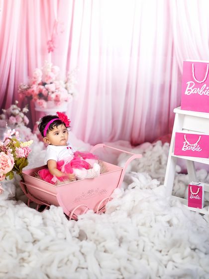 Pretty in pink and ready for her close-up. This little girl sits in her pink pram, the star of her very own Barbie-themed fairytale.