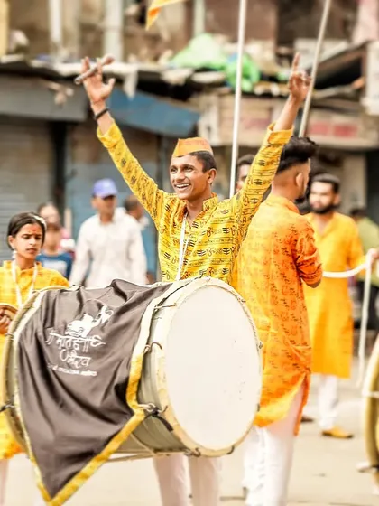 A dhol player with arms raised in celebration, his joyful expression capturing the spirit of the event.