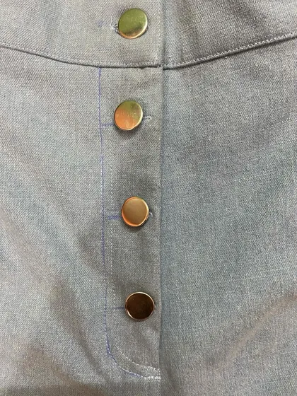The button-fly detail on a pair of custom light-wash jeans. You can choose between a zipper or a classic button-fly for your personalized pair.