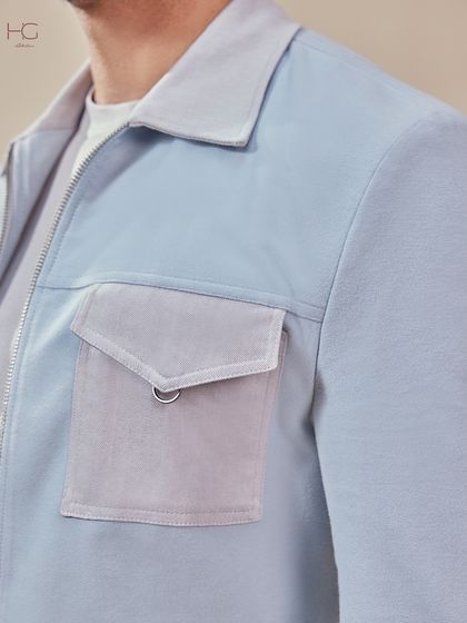 A close-up on the pocket detail of the light blue shacket, showcasing the mix of textures and hardware that gives it a unique, standout quality.