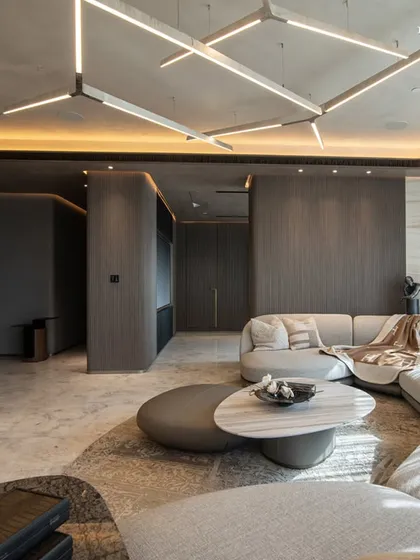 A different angle of the Lodha World View living room, showcasing the custom geometric lighting fixture that follows the curve of the ceiling. The design creates a perfect balance of opulence and elegance, embodying the family’s refined taste.