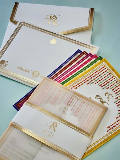 A minimalist vellum paper invitation with a belly band. The cream and gold color scheme is classic and elegant, while the colorful inserts add a touch of traditional flair.