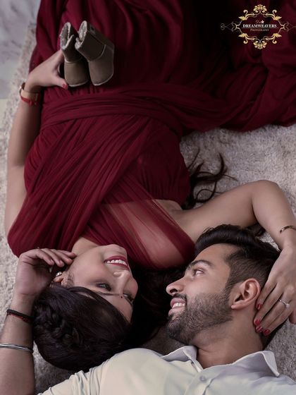 An aerial view of an expecting couple lying together, sharing a happy moment. This pose, with the tiny shoes, creates a unique and intimate portrait that tells a beautiful story.