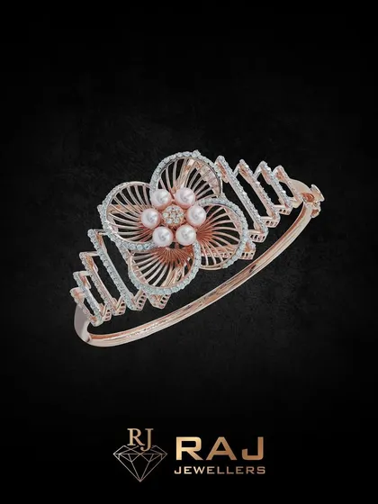 This floral-inspired kada features a large, open-petal flower with pearl accents at its center. The band has a modern, angular design, creating a beautiful contrast of styles.