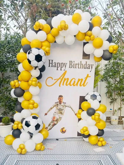 A custom birthday backdrop for a young football fan. This setup features a personalized vinyl print with Cristiano Ronaldo, framed by a balloon arch in a yellow, black, and white color scheme with football-themed balloons.