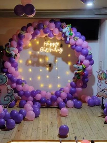 A purple and pink unicorn-themed balloon ring with a neon sign, perfect for a magical birthday photo booth.