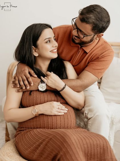 A relaxed and happy portrait of an expecting couple in our boho studio. The natural light and comfortable posing create a photo that feels both beautiful and authentic.