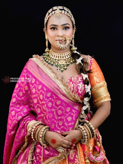 A full portrait of the bride in her magnificent pink and orange lehenga. The long, neat braid adds a classic and graceful element to her overall stunning appearance.