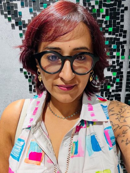 A selfie against a cool mosaic wall, with my colorful dress and signature glasses.