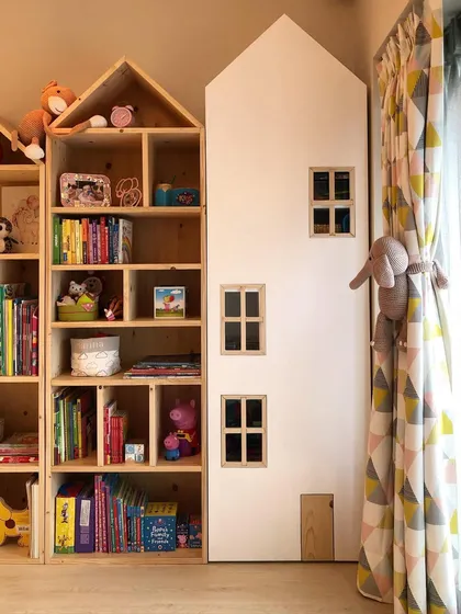 Another view of the house-shaped bookshelves, showing how they can be combined to create a "village" of storage. The natural wood finish adds warmth to the room.